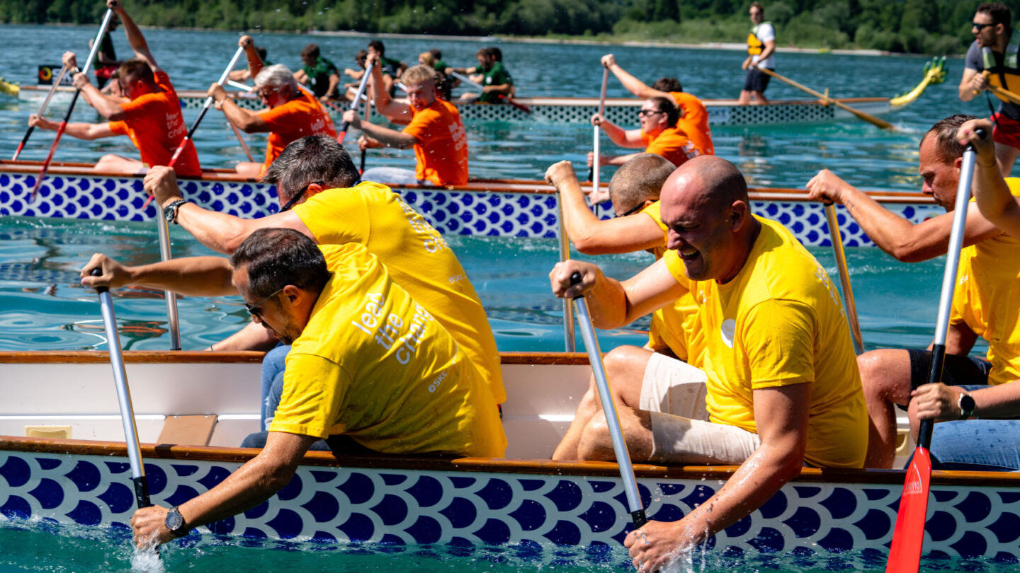 Fröhliche Menschen beim Rudern im See bei einem Teambuilding-Event