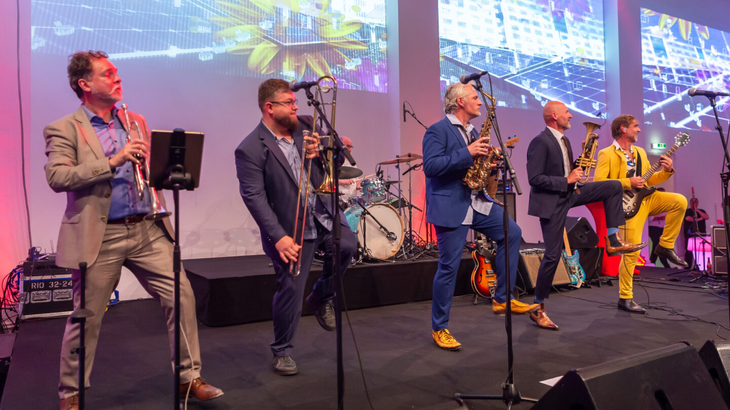 Band spielt auf Bühne mit Saxophone, Trompete und Gitarre