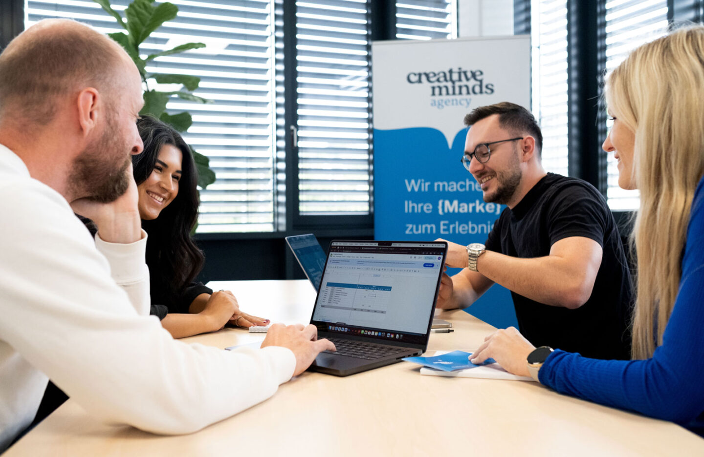 Personen die an einem Besprechungstisch sitzen und ein Projekt besprechen mit Laptops
