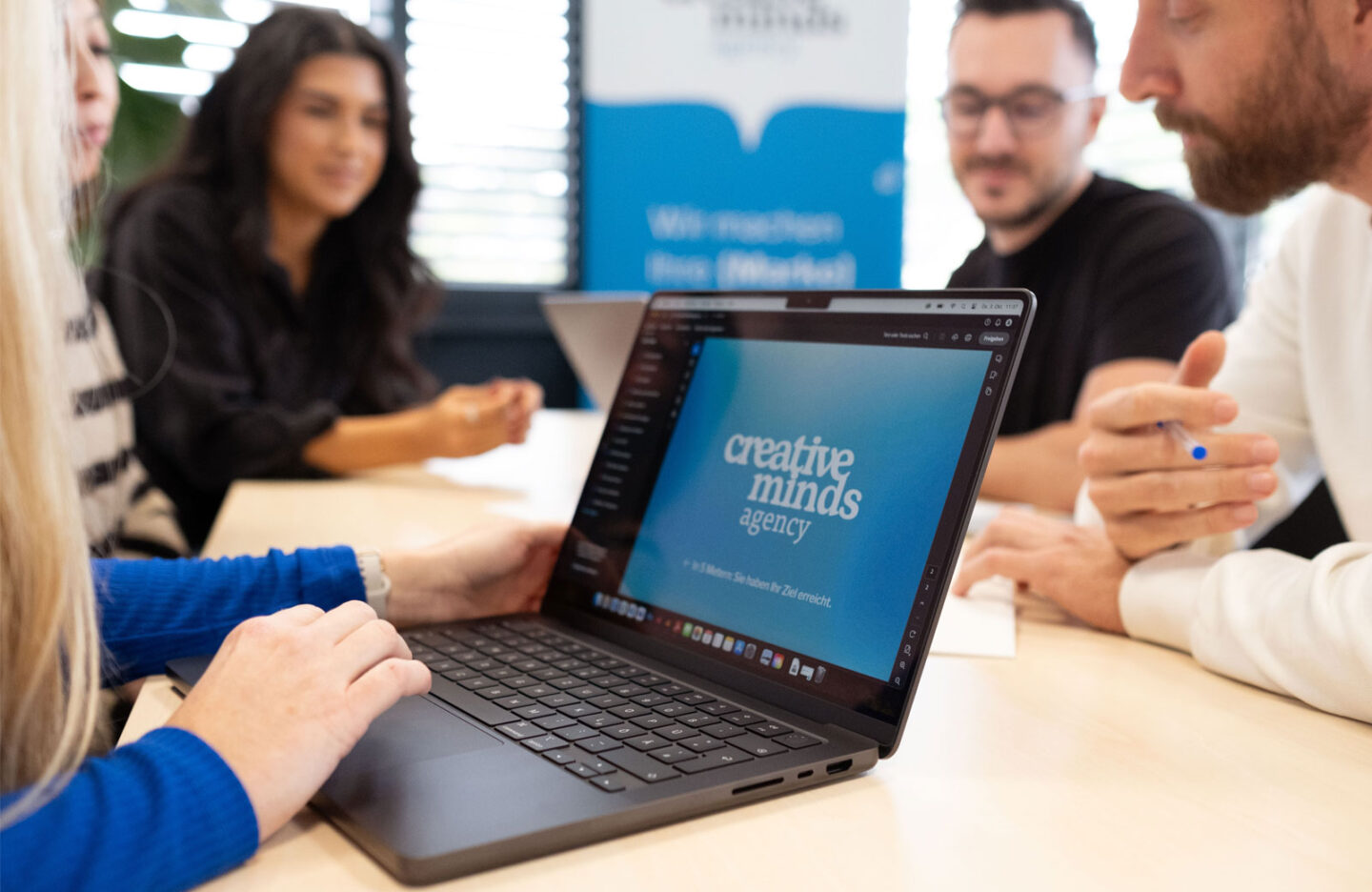 Personen die an einem Besprechungstisch sitzen und ein Projekt besprechen mit Laptops